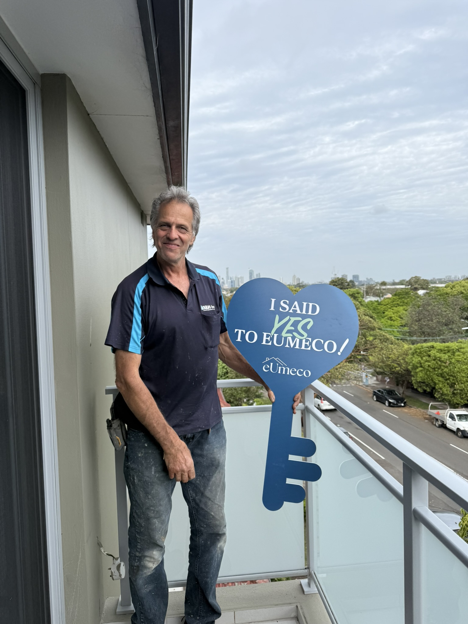 An eUmeco client on a balcony holding the blue I said YES to eUmeco key sign